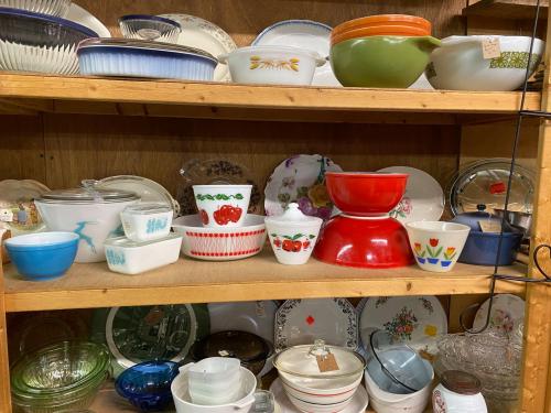 A wooden shelf filled with various colorful bowls and dishes in different shapes and sizes.