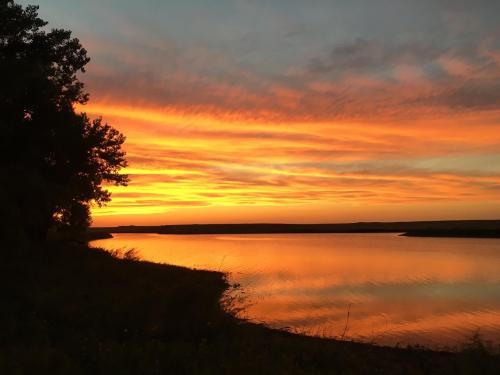 A serene sunset over a calm river, with vibrant orange and pink hues reflecting on the water's surface.