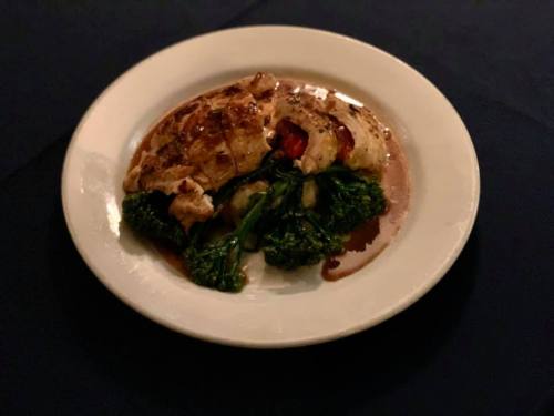 A plated dish featuring grilled chicken, roasted vegetables, and a drizzle of sauce on a white plate.