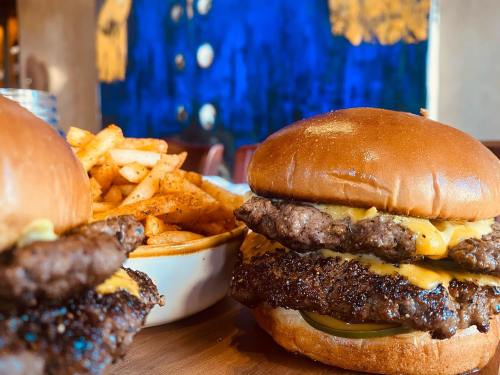 Two juicy cheeseburgers with melted cheese and pickles, served with a side of crispy fries.