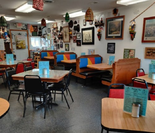 Cozy diner interior with colorful booths, wooden tables, and walls adorned with various framed photos and decorations.