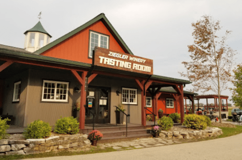Exterior of Ziegler Winery Tasting Room, featuring a red and gray building with a sign and landscaped surroundings.