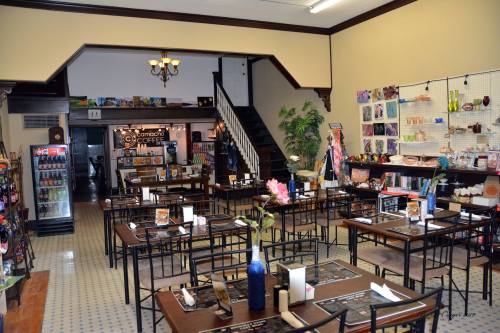 A cozy café interior with tables, a staircase, and decorative items on the walls, creating a warm atmosphere.