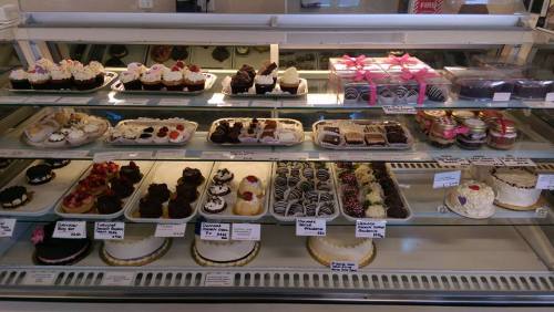 A display case filled with various cakes, cupcakes, and pastries, showcasing colorful decorations and toppings.