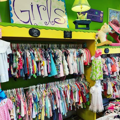 A colorful display of girls' clothing hanging on racks in a bright, cheerful store setting.