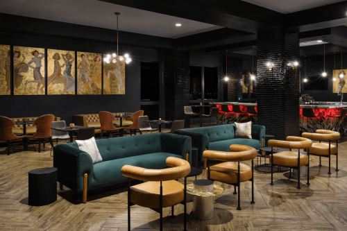 Stylish lounge with green and orange seating, modern decor, and artwork on the walls, creating a cozy atmosphere.