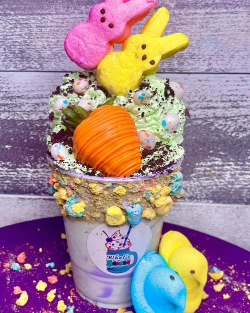 A colorful milkshake topped with marshmallow bunnies, sprinkles, and a chocolate-covered strawberry.