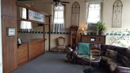 Cozy waiting area with a wooden reception desk, comfortable seating, and decorative plants.