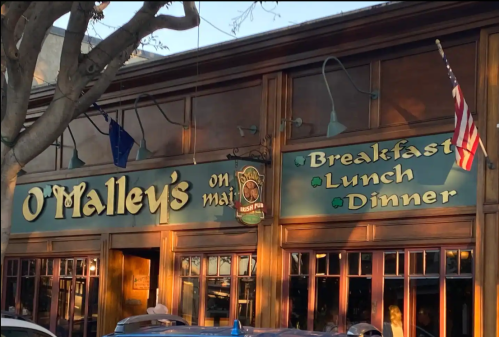 Sign for O'Malley's on Main, featuring "Breakfast, Lunch, Dinner" with an American flag and warm lighting.