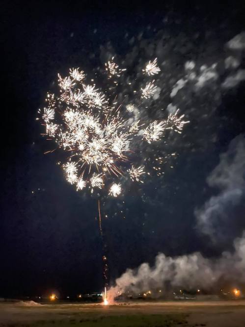 A vibrant display of fireworks lighting up the night sky, with sparks and smoke against a dark backdrop.