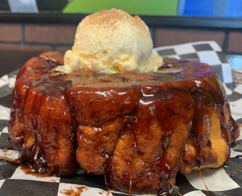 A warm, gooey dessert topped with vanilla ice cream, served on a checkered paper plate.