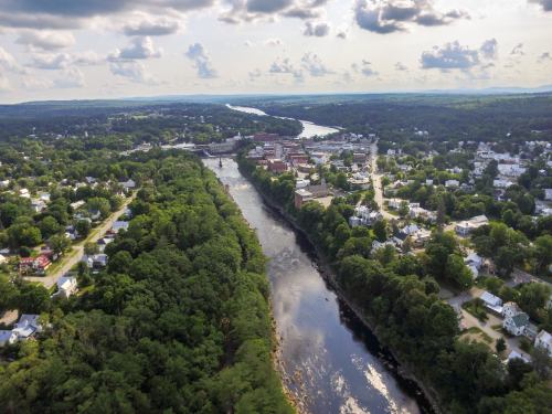 Aerial view of a river winding through lush greenery and a small town with buildings along the banks.
