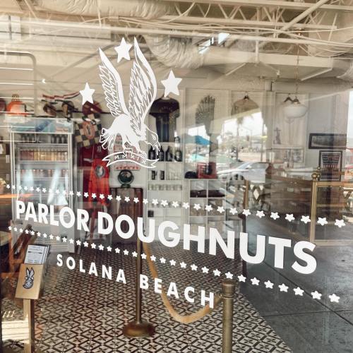Window display of Parlor Doughnuts in Solana Beach, featuring a logo and decorative elements.