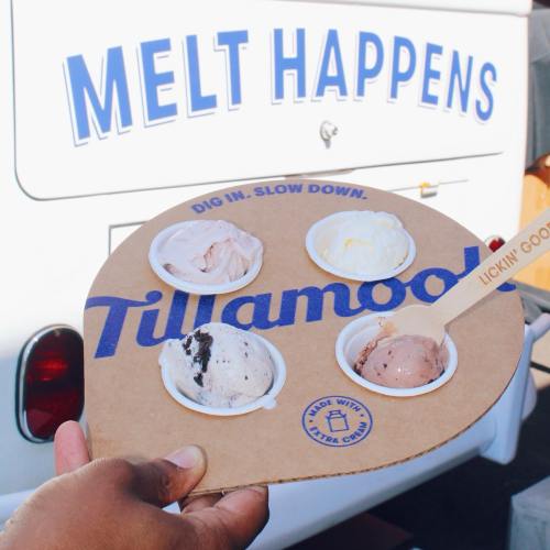 A hand holds a tray with four ice cream scoops in front of a food truck that says "Melt Happens."