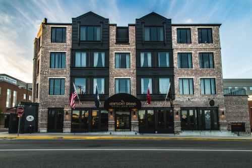 Exterior view of the Kentucky Grand Hotel, featuring a brick facade and flags, set against a clear sky.
