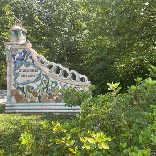 Colorful, decorative entrance to a garden, surrounded by lush greenery and trees.