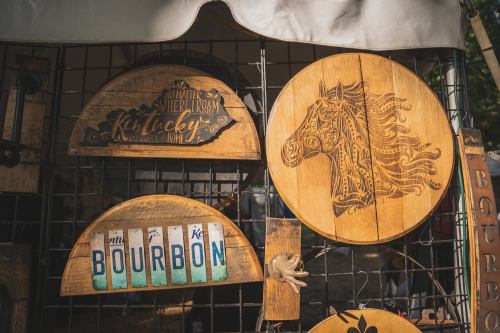 Wooden signs displayed at a market, featuring designs of a horse and the word "Bourbon."