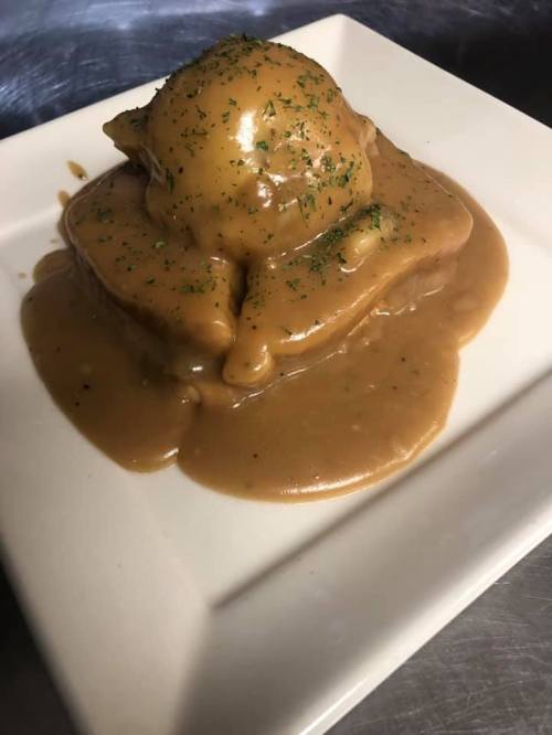 A plate featuring a mound of food topped with a glossy brown sauce and sprinkled with herbs.