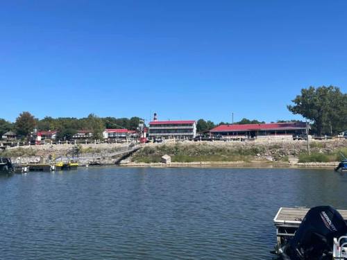 A scenic view of a lakeside resort with red-roofed buildings and a clear blue sky.