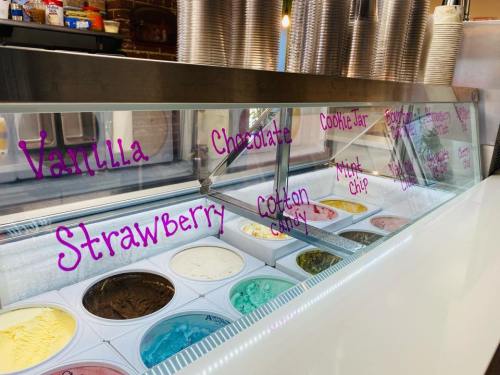 A display case of ice cream flavors, including vanilla, strawberry, chocolate, cookie jar, cotton candy, and mint chip.