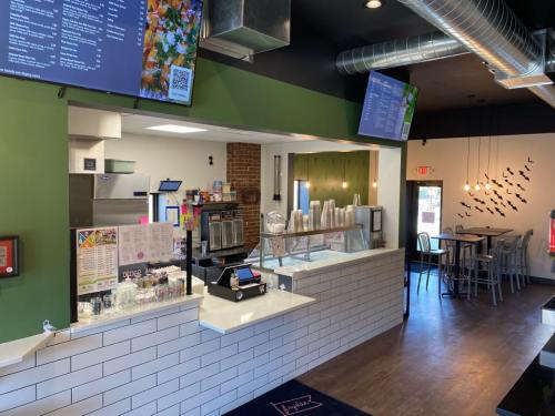Interior of a modern café with a service counter, menu boards, and seating area, featuring a green accent wall.