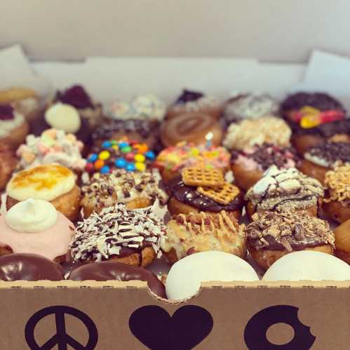 A colorful assortment of decorated donuts in a box, featuring various toppings and designs.