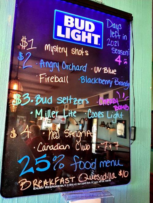 Chalkboard menu featuring drink specials and food items, including Bud Light, Angry Orchard, and breakfast quesadilla.