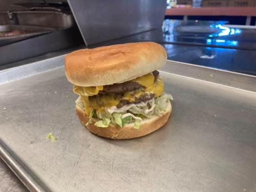 A delicious cheeseburger with two patties, melted cheese, lettuce, and mayonnaise on a toasted bun, served on a tray.