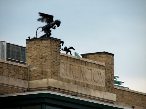 A stone building with the word "Burlington" and a decorative statue of a griffin on the roof.