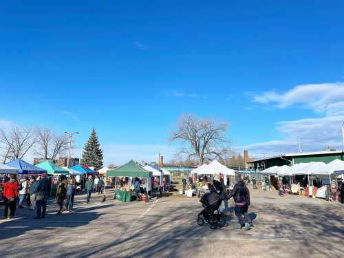 A bustling outdoor market with colorful tents, shoppers, and a clear blue sky in the background.