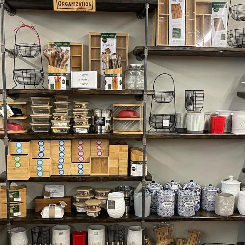 A display of various kitchen organization items, including baskets, jars, and containers on wooden shelves.