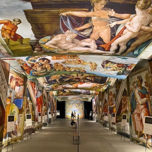 A grand hall with ceiling and wall murals depicting classical scenes, showcasing vibrant colors and intricate details.