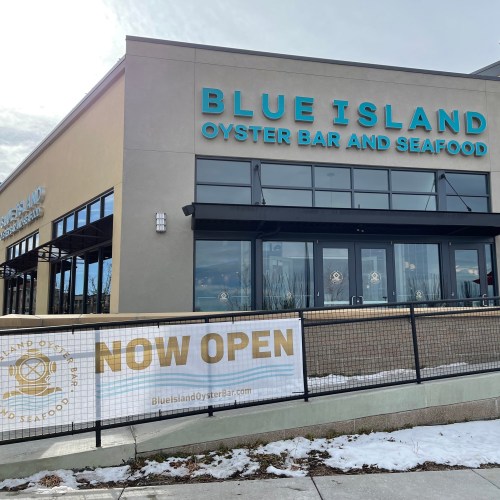 Exterior of Blue Island Oyster Bar and Seafood with a "NOW OPEN" banner in front, surrounded by snow.