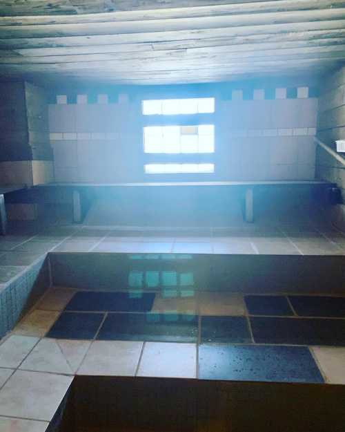 A serene sauna interior with tiled benches and a window allowing natural light to enter.