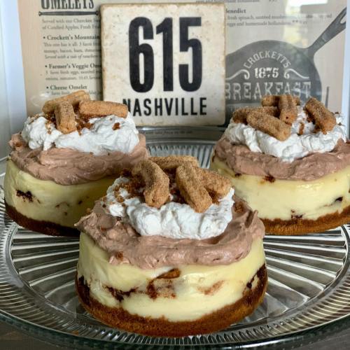 Three layered desserts with cream, chocolate topping, and crumbled cookies, displayed on a glass plate with a sign reading "615 NASHVILLE."