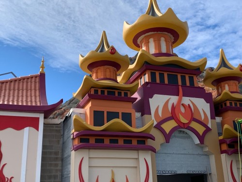 Colorful, ornate building with golden spires and flame motifs against a blue sky.