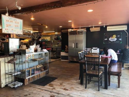 Cozy café interior with wooden floors, tables, a glass display case, and a chalkboard menu on the wall.