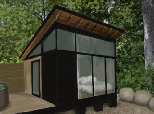 A modern cabin with large windows, surrounded by trees, featuring a bed visible inside.