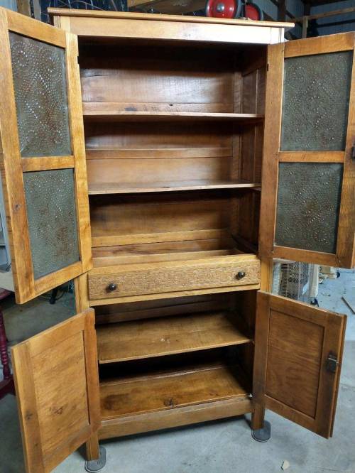 A wooden cabinet with open doors, featuring shelves and a drawer, showcasing a rustic design.
