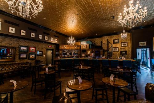 Elegant bar interior with chandeliers, wooden tables, and a spiral staircase, featuring a cozy and inviting atmosphere.