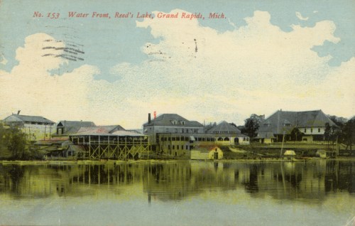 Vintage postcard depicting a lakeside view of Reed's Lake in Grand Rapids, Michigan, with buildings reflected in the water.