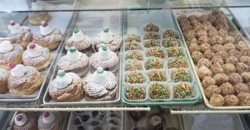 A display case filled with various pastries, including cream-topped cakes and colorful sprinkled treats.