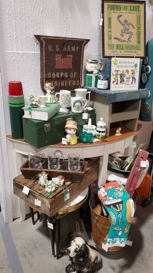 A display of vintage items including mugs, figurines, and decorations, featuring a U.S. Army Corps of Engineers sign.