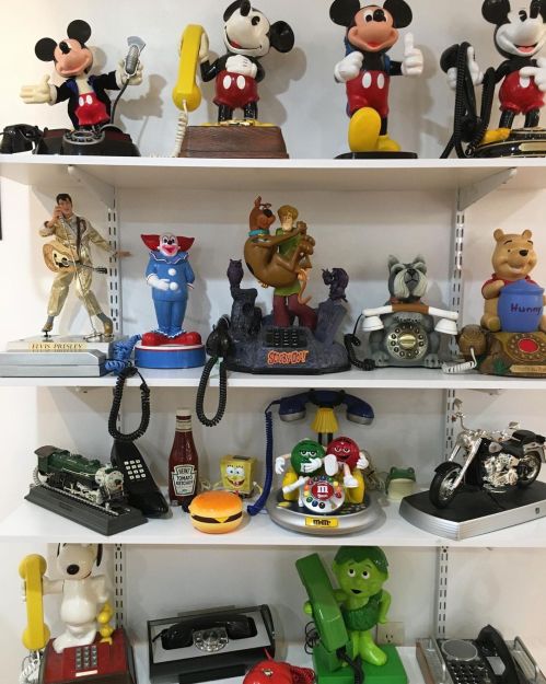 A colorful display of vintage figurines and novelty phones, featuring characters like Mickey Mouse, Scooby-Doo, and more.
