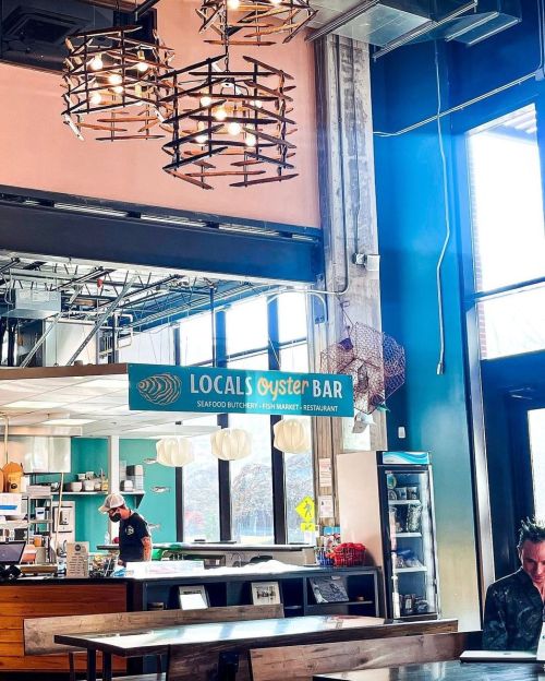 Interior of Locals Oyster Bar featuring modern decor, hanging lights, and a seafood market area.