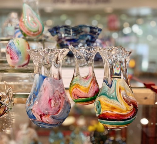 Colorful, swirled glass vases displayed in a shop, showcasing vibrant patterns and intricate designs.