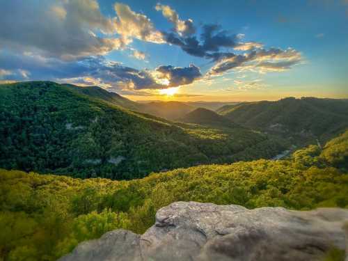 A scenic view of rolling green hills under a colorful sunset with clouds in the sky.