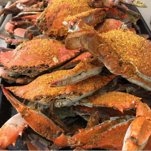 A close-up of seasoned, cooked crabs piled together, showcasing their vibrant orange shells and spices.