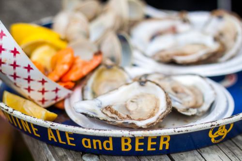 A tray of fresh oysters with lemon wedges and a side of shrimp, served on a rustic wooden table.