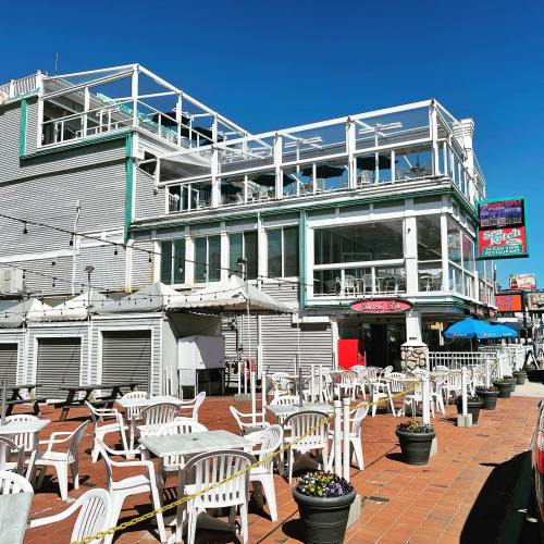 A bright, sunny day at a multi-level restaurant with outdoor seating and a clear blue sky.